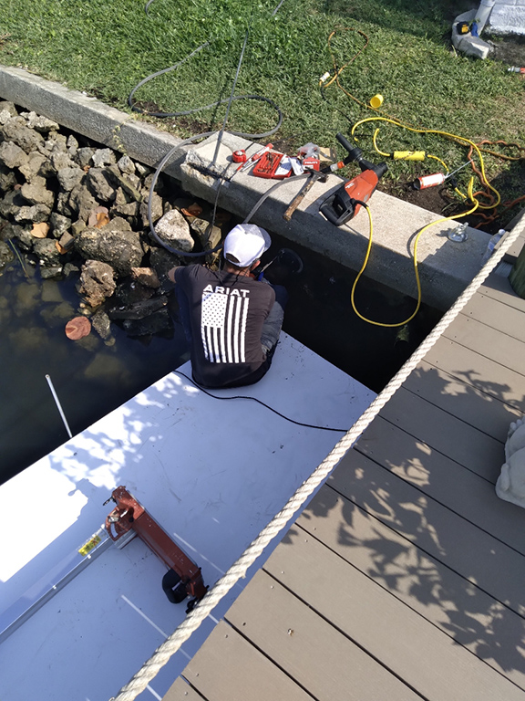 Technician repairing seawall panel from dock access